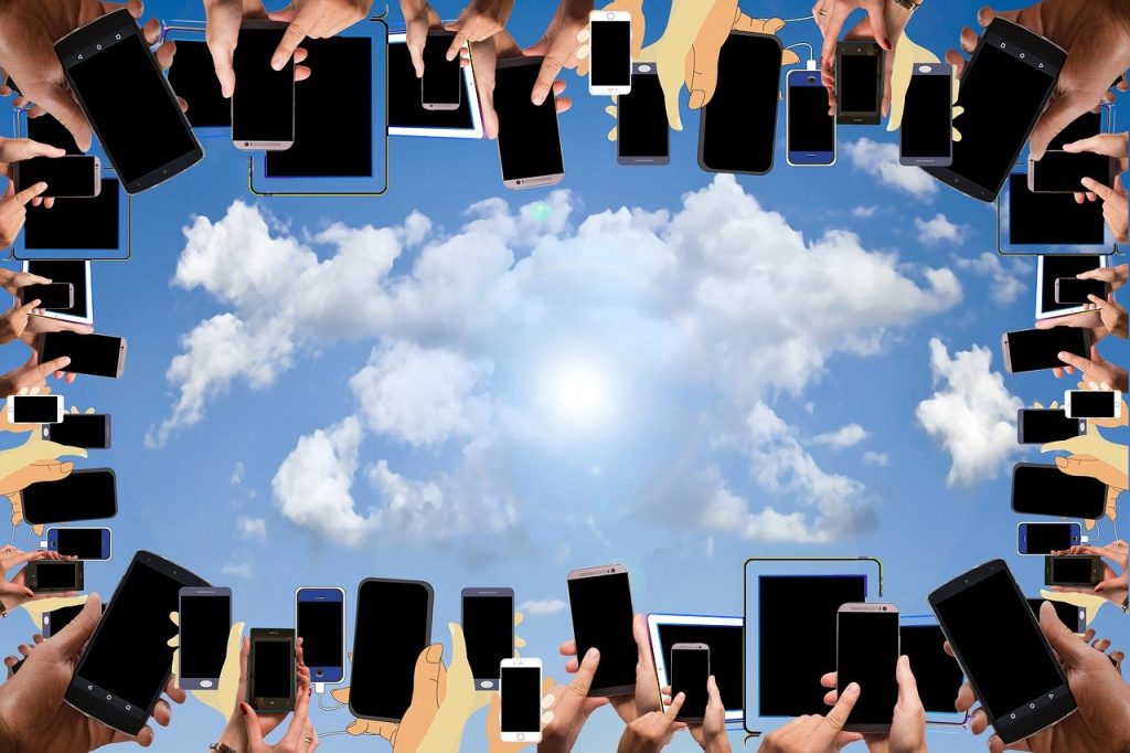 Viele Hände recken mit einem Smartphone in der Hand zum Himmel.
