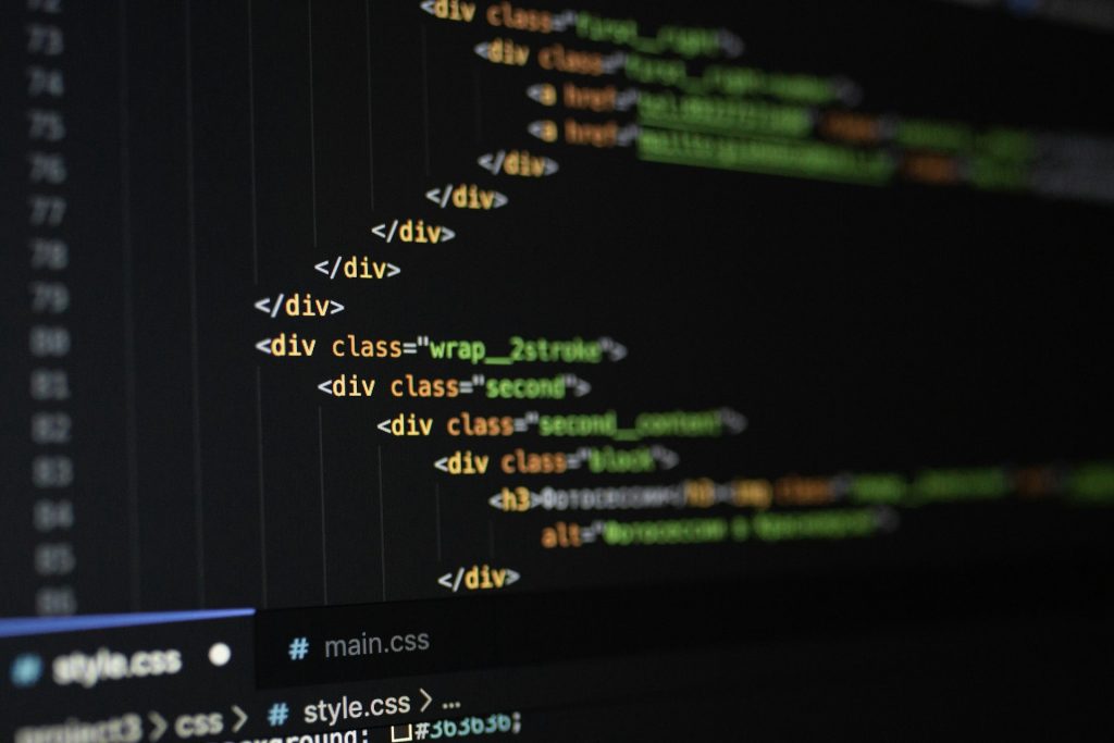 Ein Ausschnitt von HTML- und CSS-Code auf einem dunklen Bildschirmhintergrund. Im Vordergrund sind mehrere verschachtelte -Elemente mit Klassenattributen wie "wrap_2strike", "second" und "second_content" zu sehen. Am unteren Rand sind die Dateinamen "style.css" und "main.css" sowie ein Teil der Dateistruktur erkennbar.