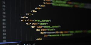 Ein Ausschnitt von HTML- und CSS-Code auf einem dunklen Bildschirmhintergrund. Im Vordergrund sind mehrere verschachtelte -Elemente mit Klassenattributen wie "wrap_2strike", "second" und "second_content" zu sehen. Am unteren Rand sind die Dateinamen "style.css" und "main.css" sowie ein Teil der Dateistruktur erkennbar.